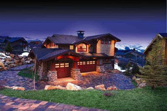 large home in a mountainous area with two wayne-dalton 9800, faux wood grain style, fiberglass residential garage doors at dusk