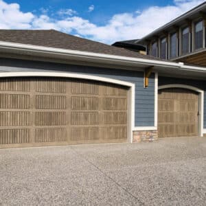 two different sized sonoma clay colored wayne-dalton 9800, faux wood grain style, fiberglass residential garage doors on a large home