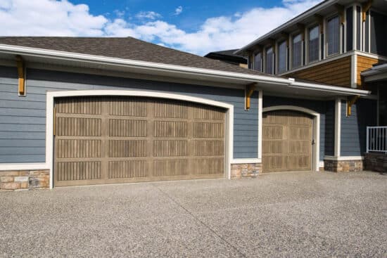 two different sized sonoma clay colored wayne-dalton 9800, faux wood grain style, fiberglass residential garage doors on a large home