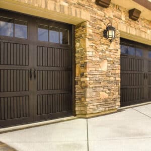 closeup of a stone home with two dark walnut colored wayne-dalton 9800, faux wood grain style, fiberglass residential garage doors