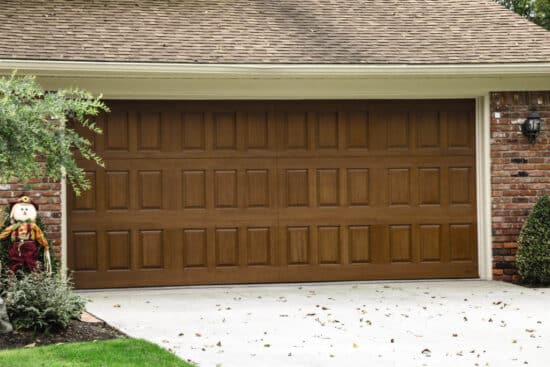 closeup of a home with a natural oak colored wayne-dalton 9800, faux wood grain style, fiberglass residential garage door