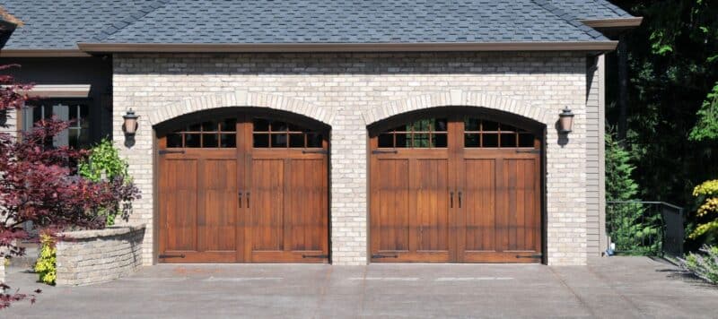 two brown garage doors on a white stone residential house