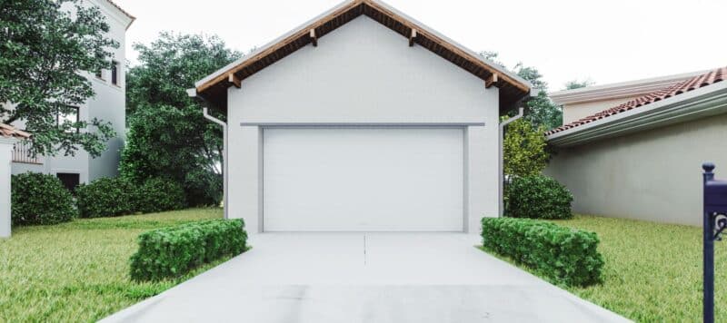 Modern residential garage with a white roll-up door, surrounded by neatly trimmed shrubs and greenery