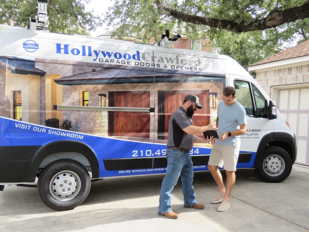 Garage door installer talking with homeowner next to branded company van