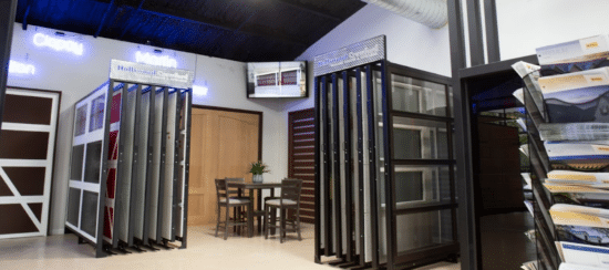 A modern showroom displaying various garage door panels and a central seating area under bright neon lighting