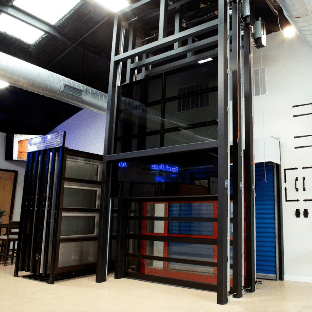 Tall glass and metal garage doors on display in a showroom with industrial-style decor and bright lighting