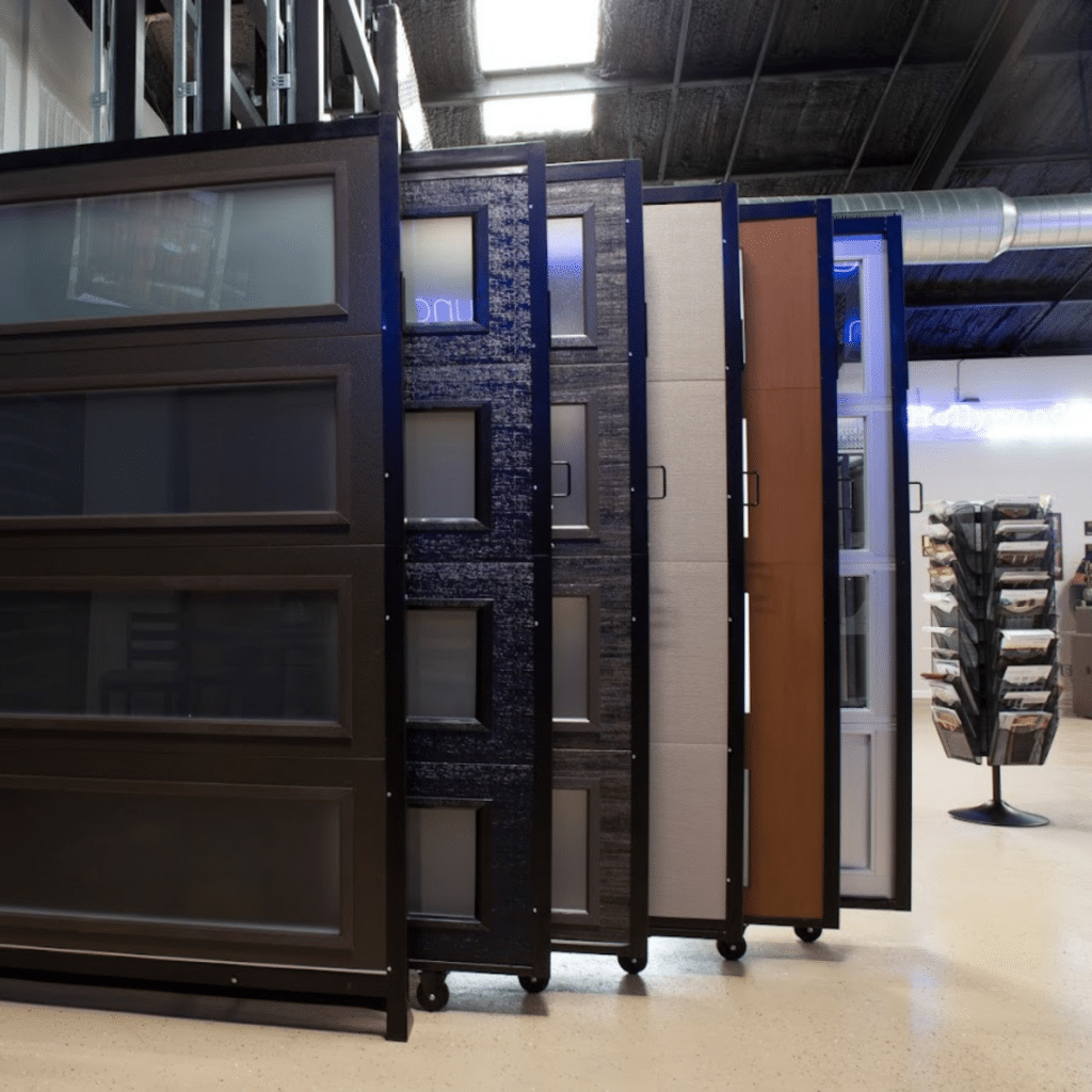 Close-up of garage door panel samples in various textures and colors, showcased on movable racks in a showroom