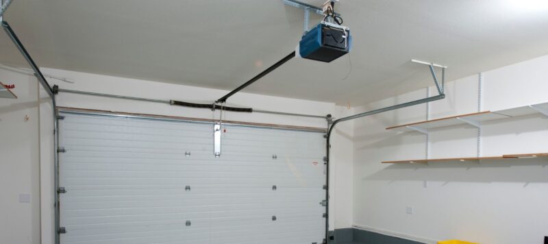 empty garage with new white garage door and garage door opener installed on the ceiling