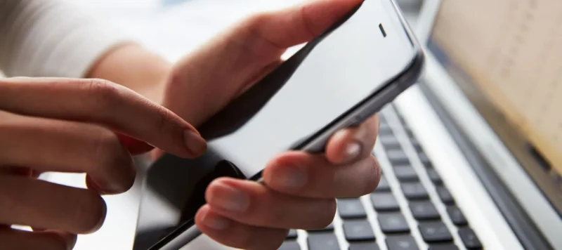 close up of a person at laptop using mobile phone